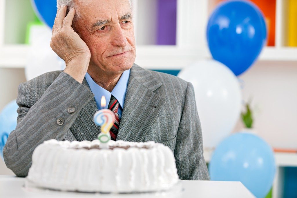 Senior man sitting front of birthday cake
