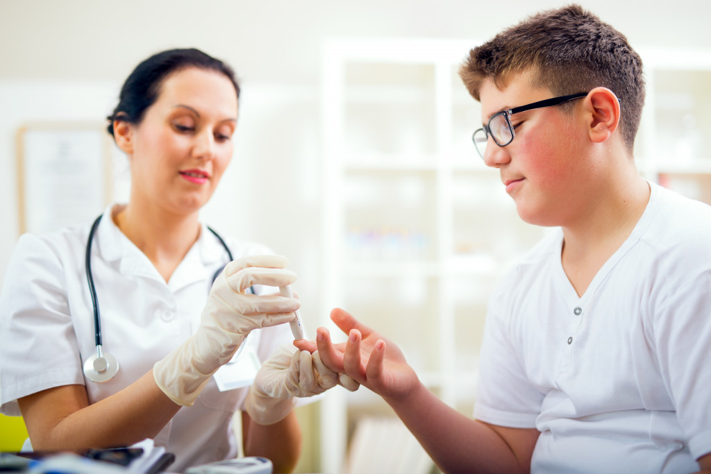 kid getting tested for his blood sugar by a nurse