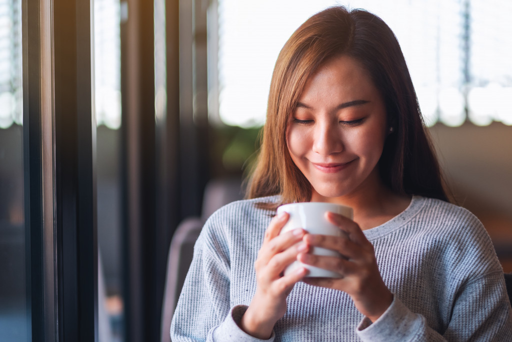 a young woman holding and looking at her coffee 