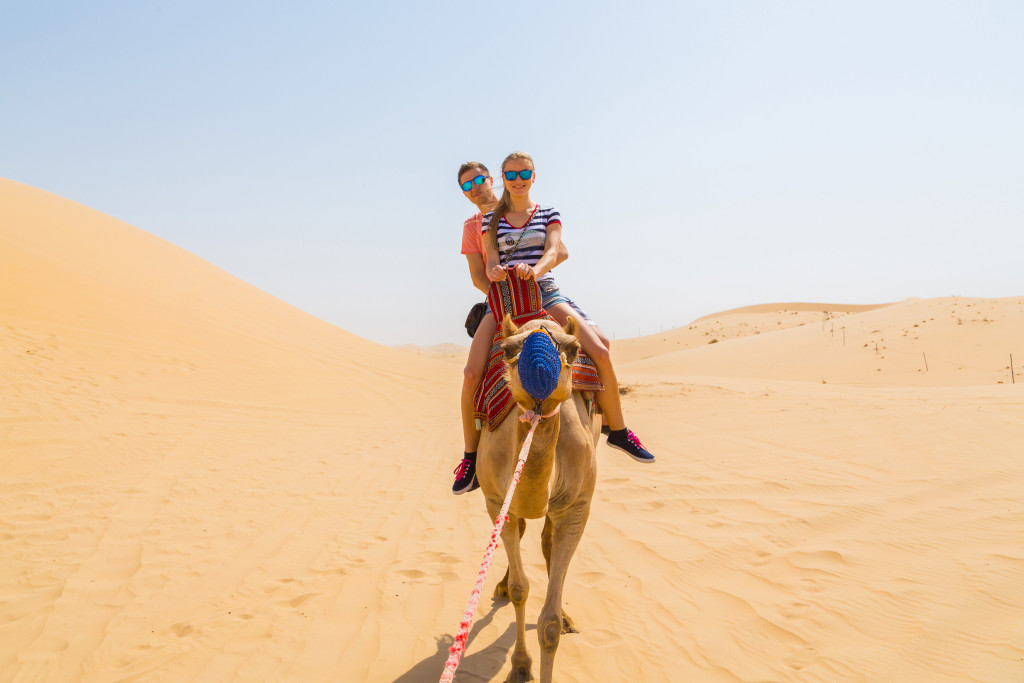 couple riding a camel in the desert