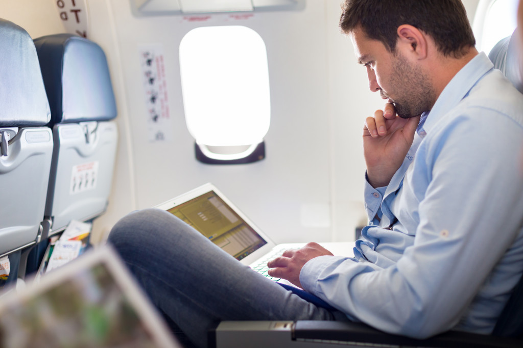 man sitting on an airplane with laptop on his lap