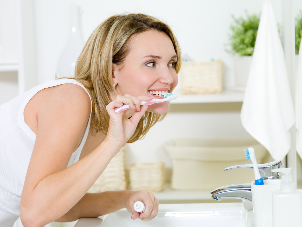 woman smiling in the mirror while tooth brushing