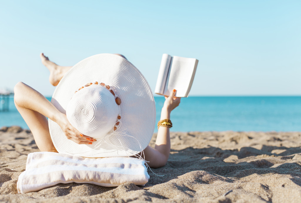 A woman sunbathing at a beach while reading a book