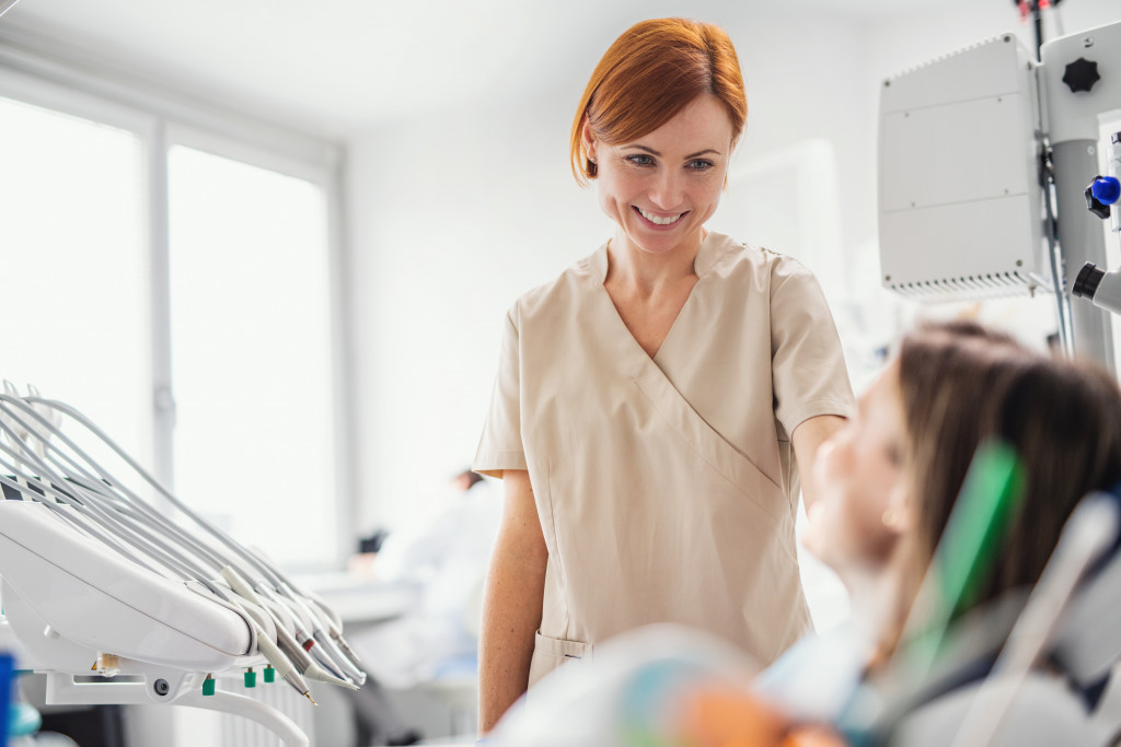 A dentist talking to a woman patient sitting on a dental chair in a clinic