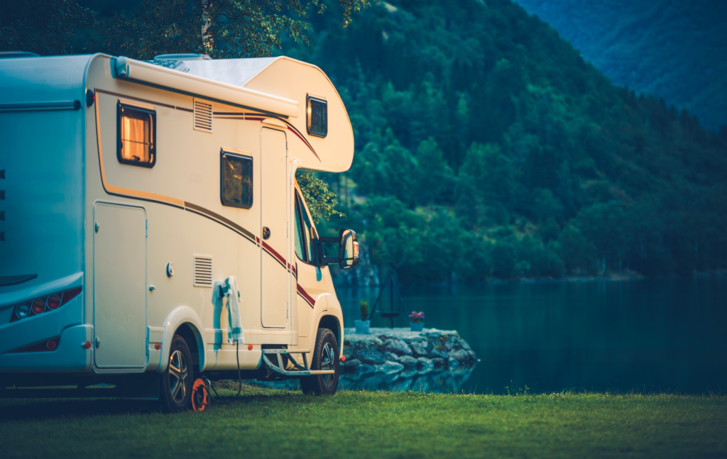 a white camper parked beside a lake