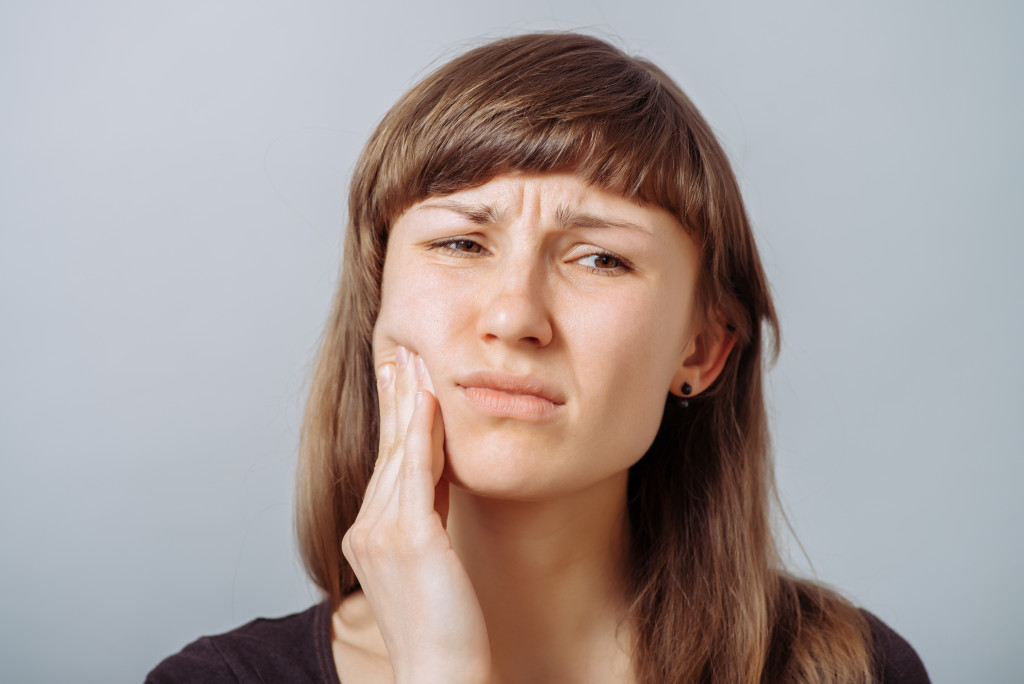 woman with toothache against gray background