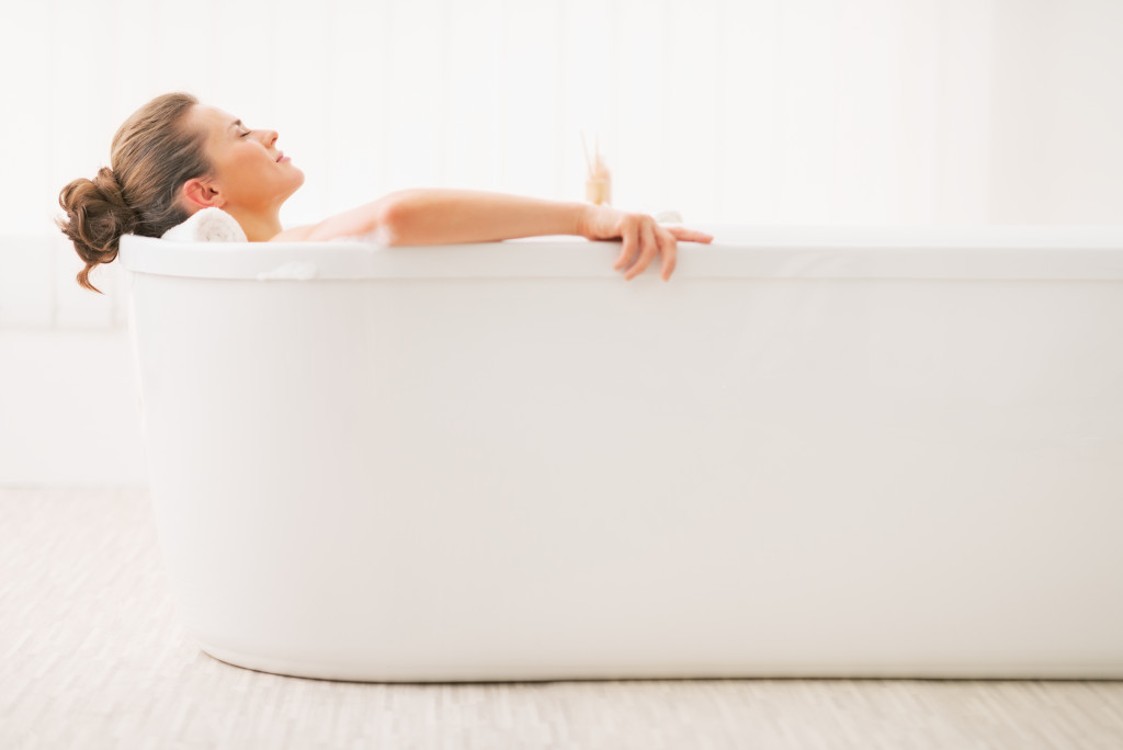 woman relaxed with closed eyes in bath tub all white