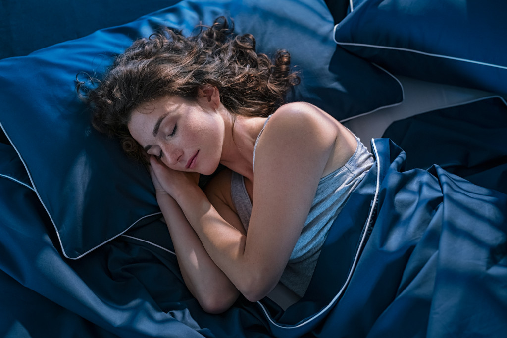 woman peacefully sleeping in blue-themed bed