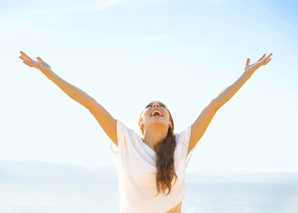 woman smiling while stretching arms outward with sky as background