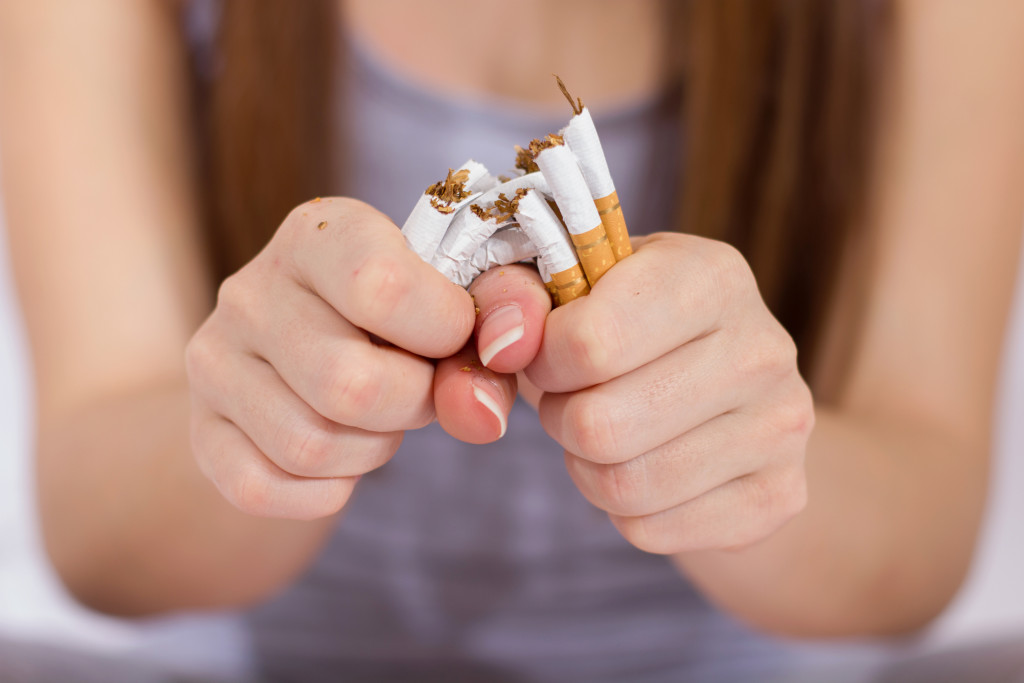 quit smoking concept woman breaking a bunch of cigarettes