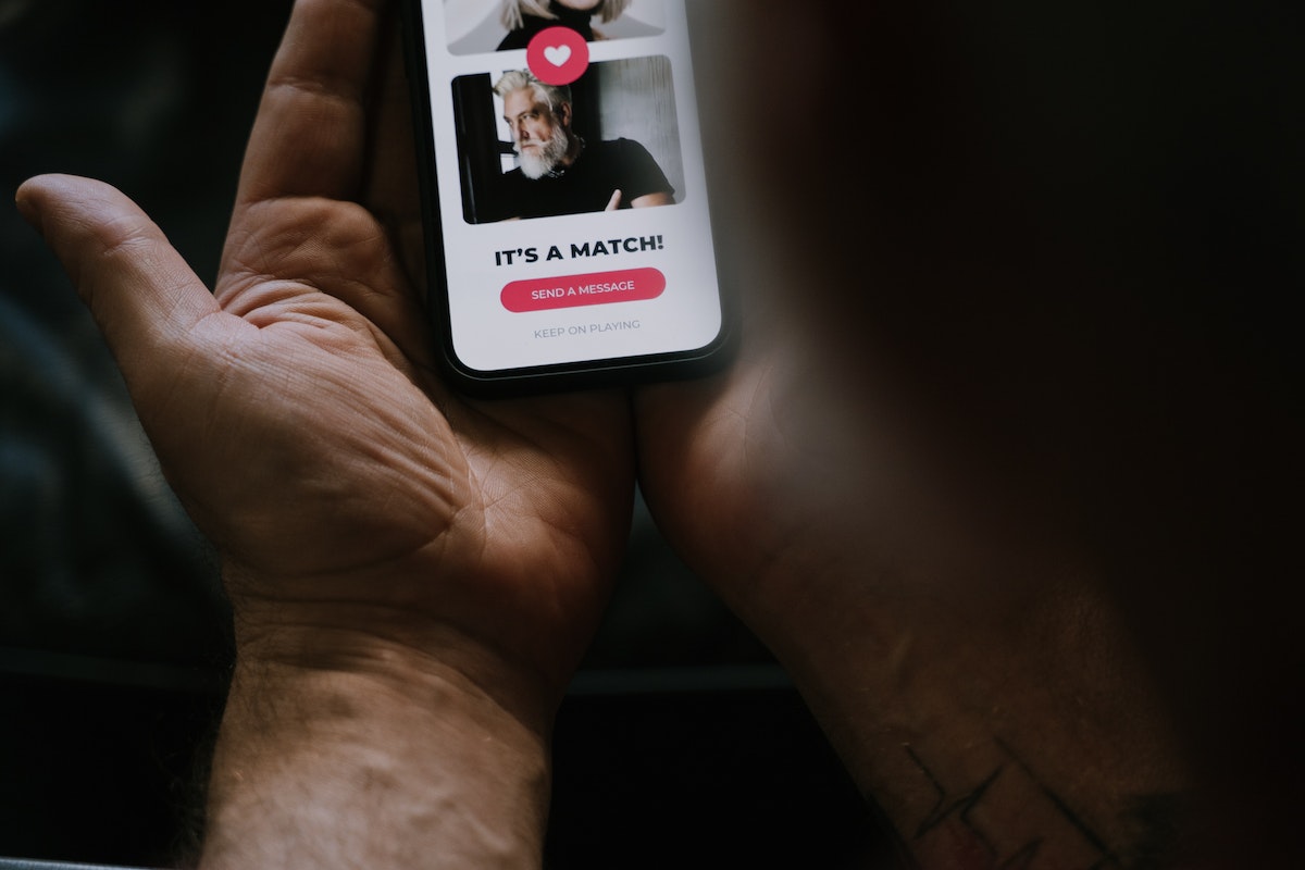 Human Hands Holding a Smartphone with Dating-Matching App on Screen