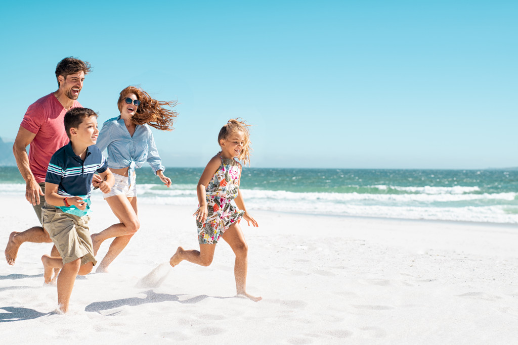 Small family running on the beach on a sunny day.