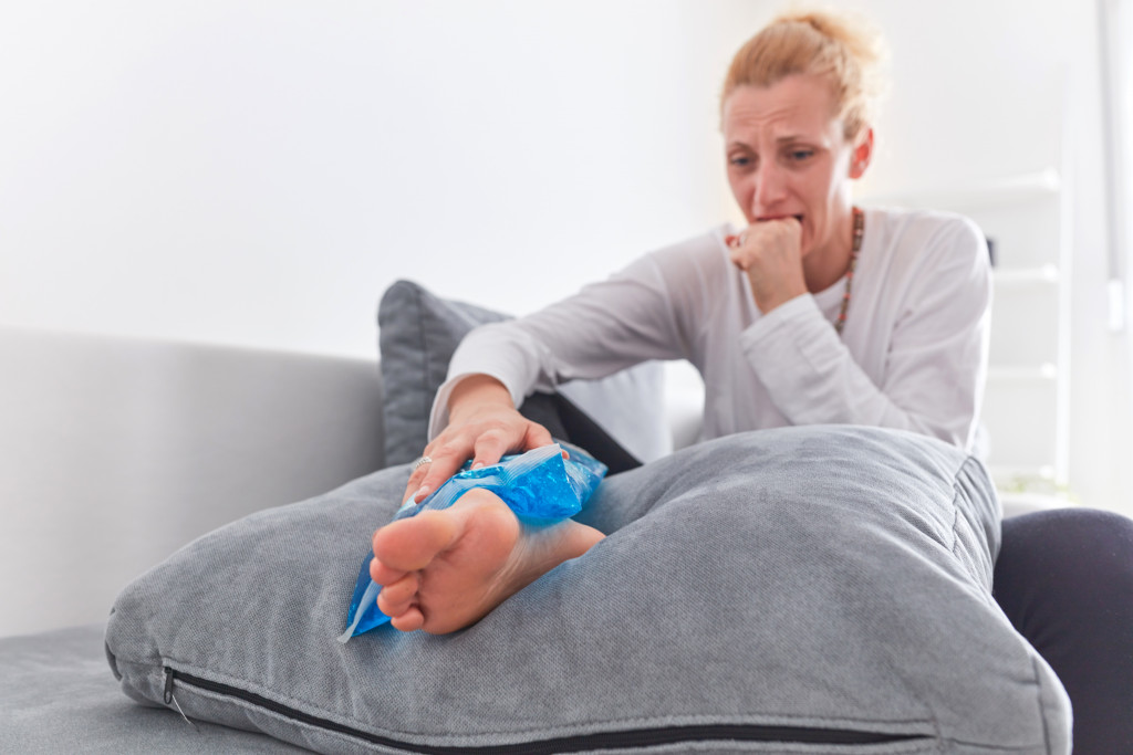 woman holding ice pack on ankle pain