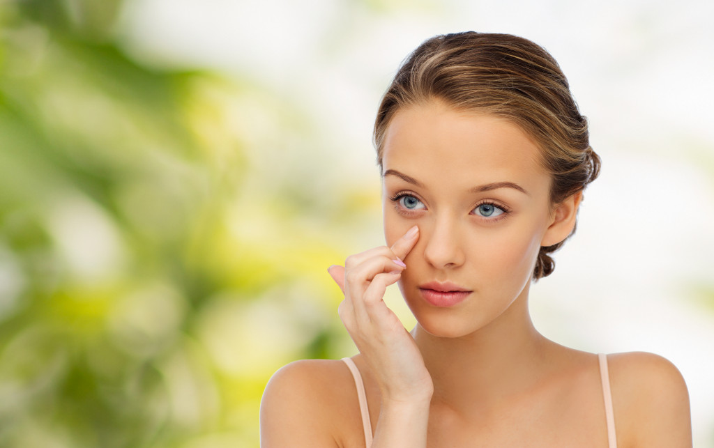 woman adding cream in her face in the outdoors