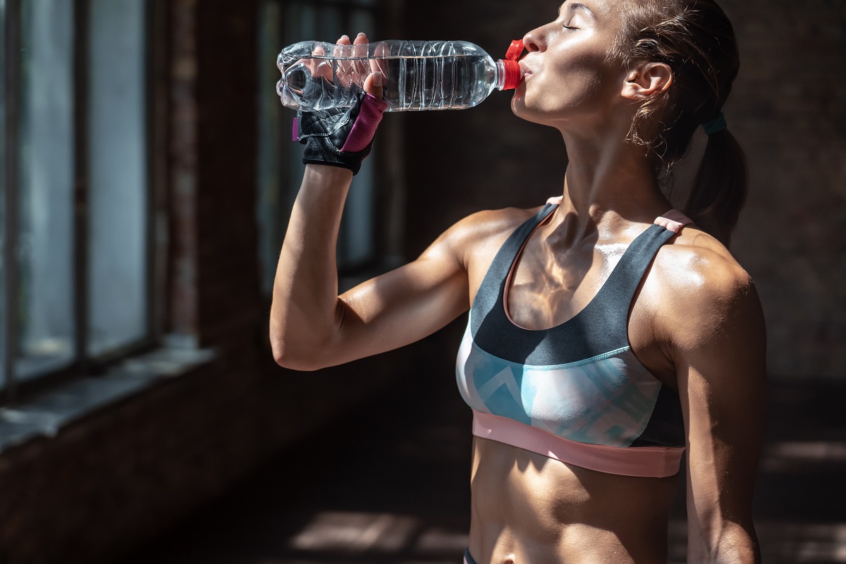 a woman drinking water after workout